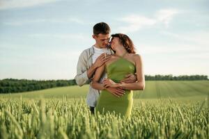 Standing, and enjoying nature and each other. Lovely couple are on the agricultural field together photo