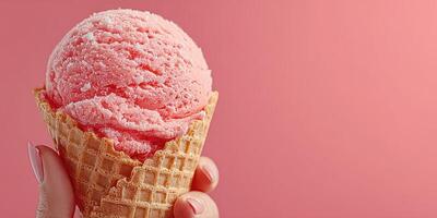 Hand holding a pink ice cream cone against a pastel background during a warm day photo