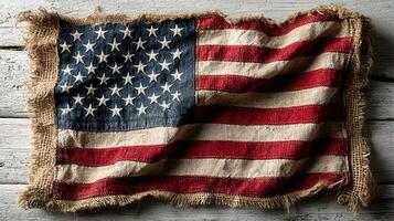 Worn American flag displayed on a rustic wooden surface highlighting the texture and colors of the national emblem photo
