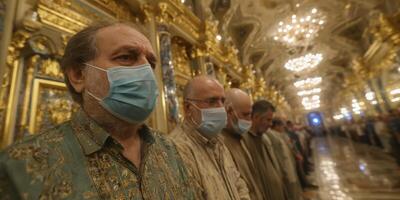 Religious gathering occurs in ornate hall with participants wearing masks during a ceremonial event photo