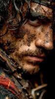 Warrior with dirt and mud on face displays intensity and strength in close-up portrait taken in a dramatic setting photo