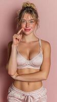 Woman in light pink lingerie poses confidently against a soft pink background during a casual indoor setting photo