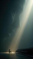 Person sitting in an empty auditorium with a large light beam illuminating their figure and a shadowed face in the background photo