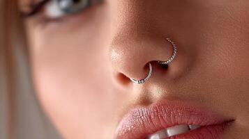 Close-up of a person showcasing multiple nose piercings in a modern aesthetic setting during daylight photo