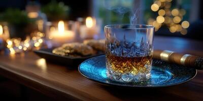 Warm light from candles illuminates a glass of whiskey and snacks on a wooden table during an evening gathering photo