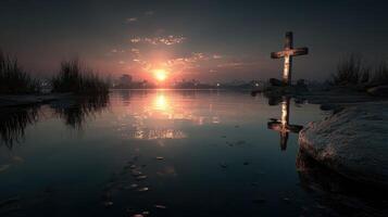Sunset reflection on calm waters with a cross and rocks amidst tall grass in a serene landscape photo