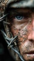 Soldier covered in mud and debris stares intensely into the distance during a military exercise in a forest environment photo