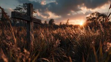 Sunset over a grassy field with a wooden cross marking a serene memorial site photo