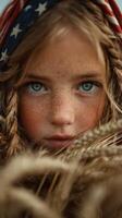 Young girl with striking blue eyes and long hair among golden wheat fields in warm summer light photo