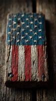 Weathered wooden plank painted with American flag design resting on textured rustic surface photo