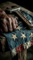 Hands resting on a weathered American flag while holding a rusty wrench in a dim workshop setting photo