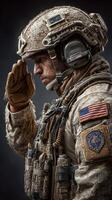 Soldier saluting in combat gear with U.S. flag displayed during a somber remembrance event photo