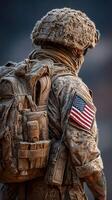 Soldier in dusty combat gear stands with American flag patch in rugged terrain during military operation photo