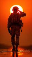 Soldier saluting against a dramatic sunset in a moment of reflection and respect photo
