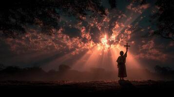 Silhouette of a person holding a cross against a dramatic sunset in a serene landscape photo