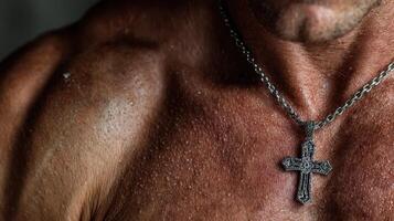 Muscular man showcasing a silver necklace with a cross in a well-lit indoor setting photo