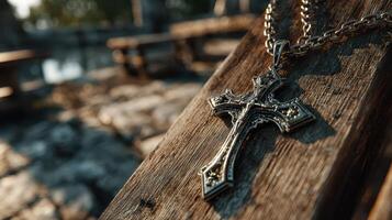 Cross necklace resting on weathered wood near water at sunset showcasing intricate design and reflections photo