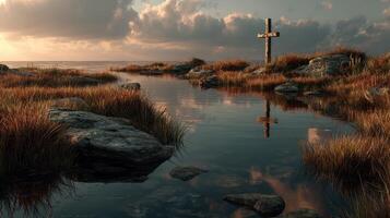 Reflection of a cross at sunset over calm waters surrounded by tall grass and rocks photo