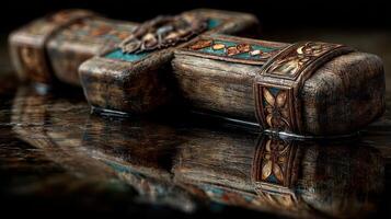 Intricately carved wooden cross with turquoise inlays resting on a reflective surface photo