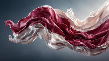 Flowing fabric with red and white colors undulates gracefully in a light backdrop photo