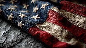 Old American flag folded on dark stone surface with visible texture and colors representing patriotism and history photo