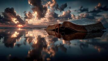 Open book resting on calm water reflects a stunning sunset with dramatic clouds and golden light photo