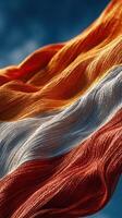 Colorful fabric waves in the wind during a sunny day, showcasing vibrant hues of orange, white, and red photo