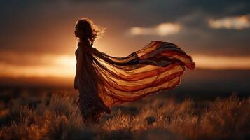 Girl in flowing fabric stands against sunset backdrop in open field photo