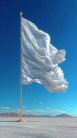 Large white fabric flag billowing in the wind against a clear blue sky in a desert landscape photo