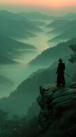 Warrior stands on cliff overlooking misty valley at dawn with sword ready photo