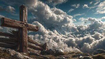Clouds surround a wooden cross on a mountain peak under a dramatic sky at sunset photo
