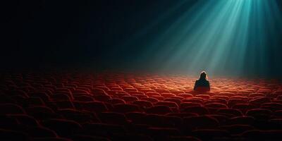 Lonely figure seated in empty theater illuminated by soft, dramatic light photo