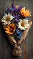 Colorful bouquet of dried flowers wrapped in brown paper on rustic background photo