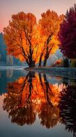 Autumn trees reflecting in a calm lake during sunrise in a vibrant landscape photo