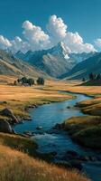 Majestic mountains surround a serene river flowing through a golden grassy valley under a blue sky photo