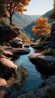 Vibrant autumn landscape featuring a serene stream winding through rocky terrain in a forested valley photo