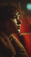 Young woman gazes thoughtfully in a dimly lit theater with red seating, capturing a moment of introspection photo