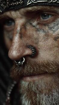 Close-up portrait of a man with intricate facial piercings and weathered skin in a dark, atmospheric setting photo