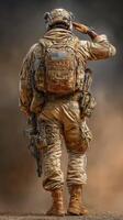 Soldier saluting in tactical gear against a dusty background at sunset during a military operation photo