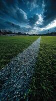 Cloudy sky over a green soccer field with a clear white line marking the boundary at dusk photo