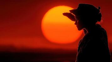 Woman silhouetted against a vibrant sunset while saluting and reflecting in a serene landscape photo