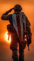Soldier saluting against a vibrant sunset backdrop with tattered flag draped over shoulders at military training exercise photo