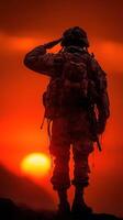 Soldier saluting at sunset with warm orange hues in the background while honoring service and sacrifice during evening hours photo