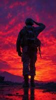 Soldier saluting against a vibrant sunset backdrop in a military setting photo