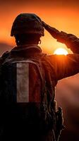 Soldier saluting at sunrise with a backpack amidst a colorful sky and misty landscape photo