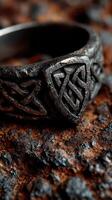 Detailed view of intricate black ring resting on textured surface with rough stones photo