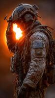 Soldier standing at sunrise saluting while wearing tactical gear in a desert landscape photo