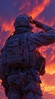 Soldier saluting against a vibrant sunset sky in a display of respect and honor photo