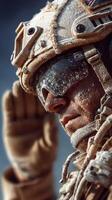 Soldier in tactical gear saluting in a harsh, sandy environment during a military operation photo