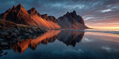 Majestic mountains reflect in calm waters during sunrise at a coastal location in Iceland photo